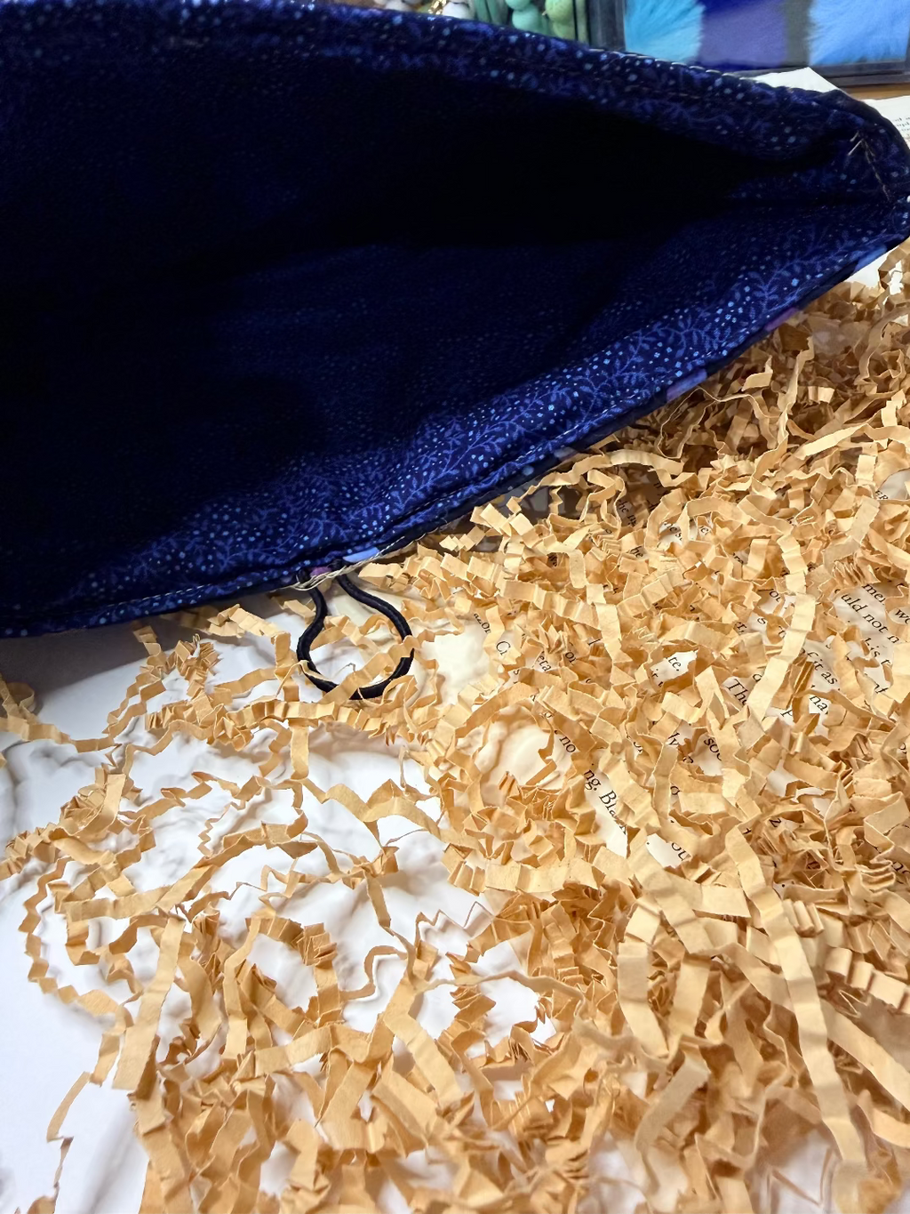 Blue interior of quilted book sleeve on top of crumpled gold paper