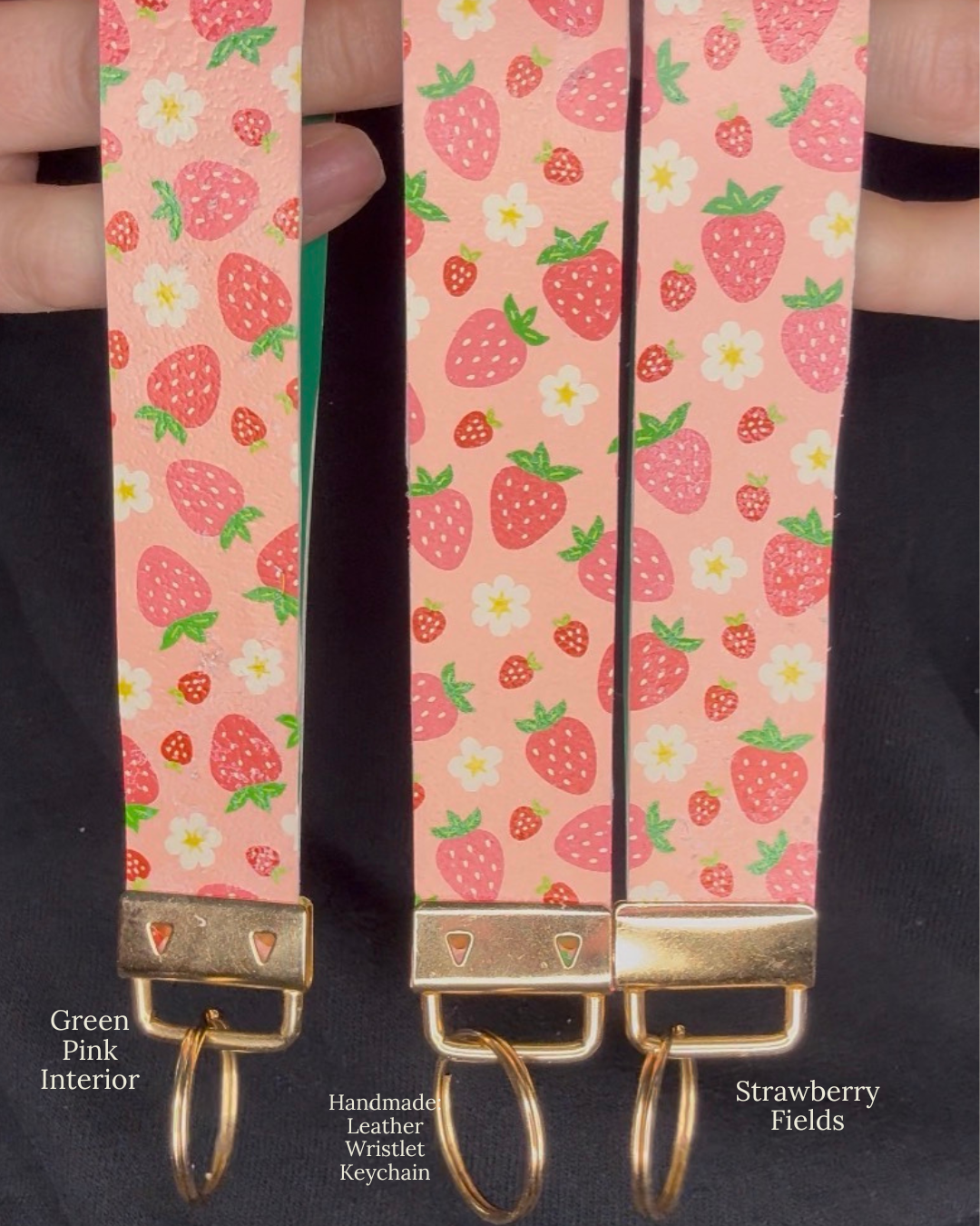 Strawberry patterned keychain with gold clasp on a black background